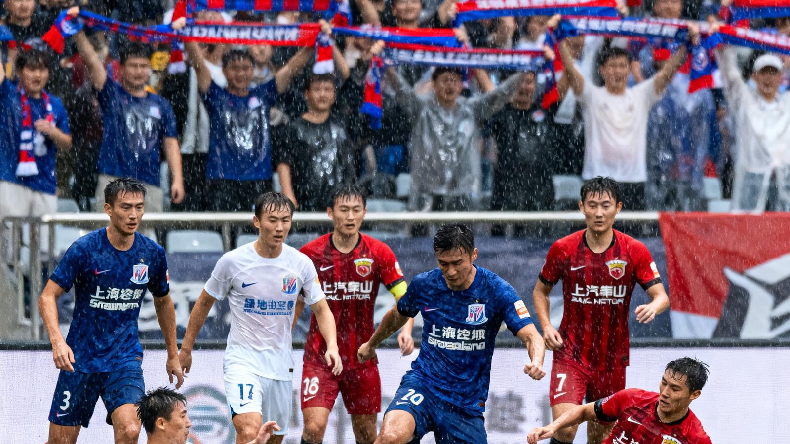 中超上海德比申花对阵海港，球员在雨中激烈拼抢，看台球迷举起围巾